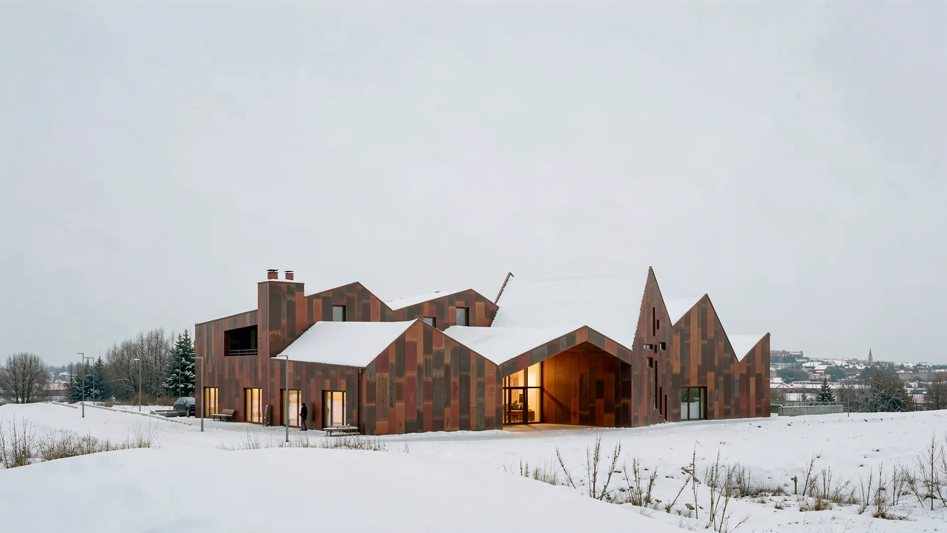 Fotorealistische Winter-Visualisierung desselben Giebeldach-Ensembles mit rostroter Cortenstahlfassade in verschneiter Landschaft